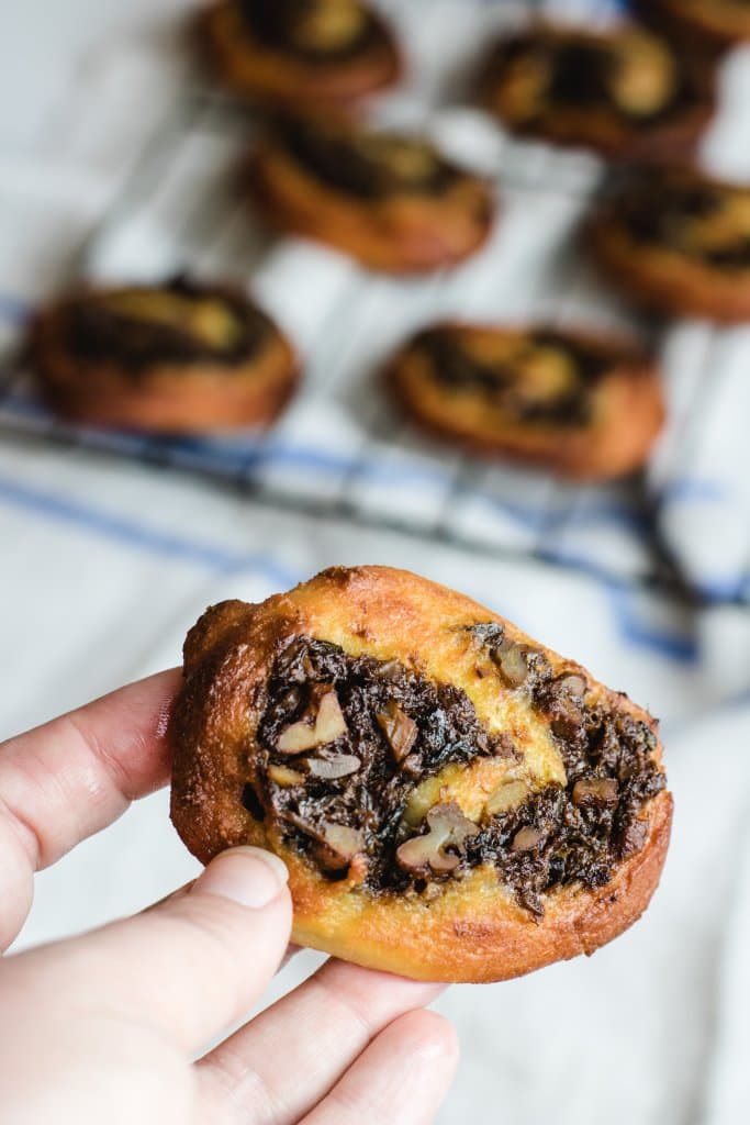 a keto fruit mince scroll being held with a cooling rack in the background with scrolls on it. 