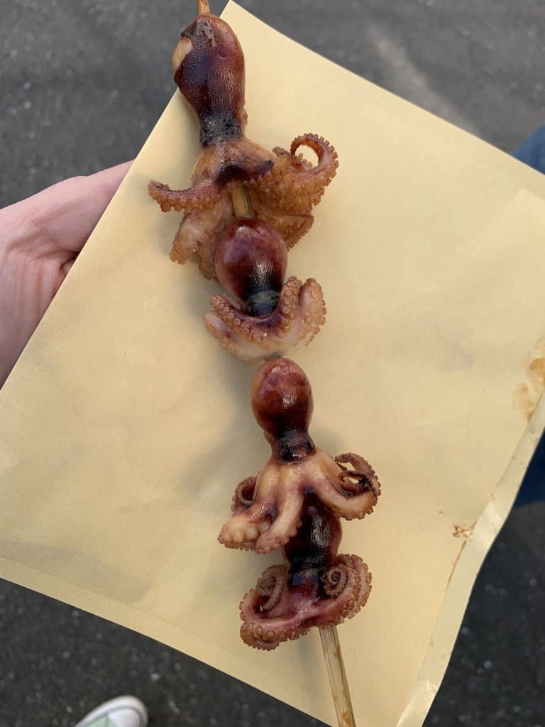 4 baby octopus on a skewer on a brown paper bag