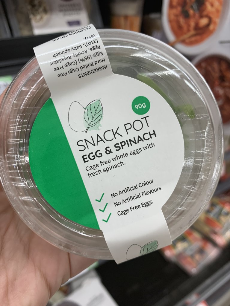 Hand holding egg and spinach snack pot. A perfect keto snack at Coles. 