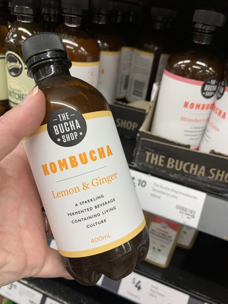 Hand holding kombucha bottle. A perfect keto snack at Coles. 
