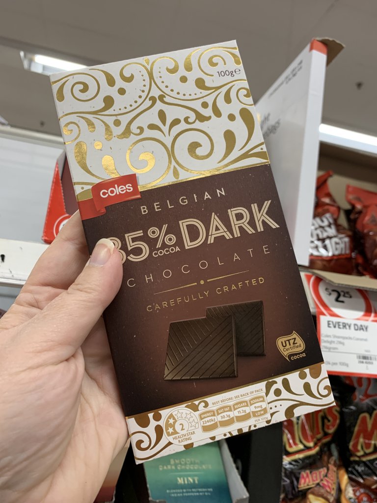 Hand holding 85% Coles dark chocolate. A perfect keto snack at Coles. 