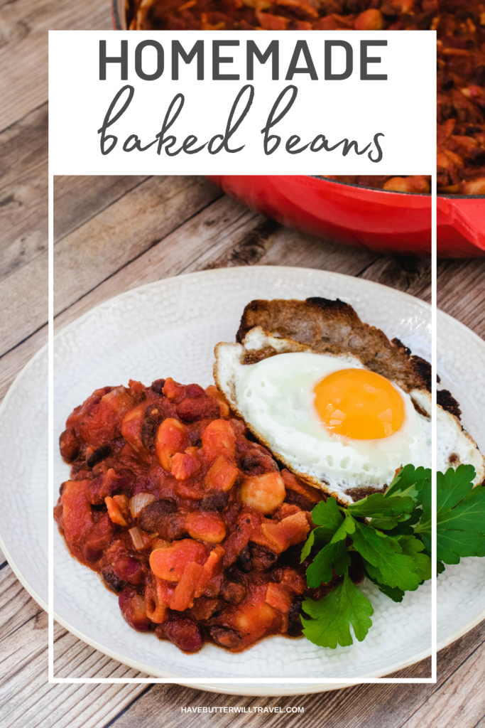 Homemade baked beans on a white plate with a fried egg on toast and sprig of parsley
