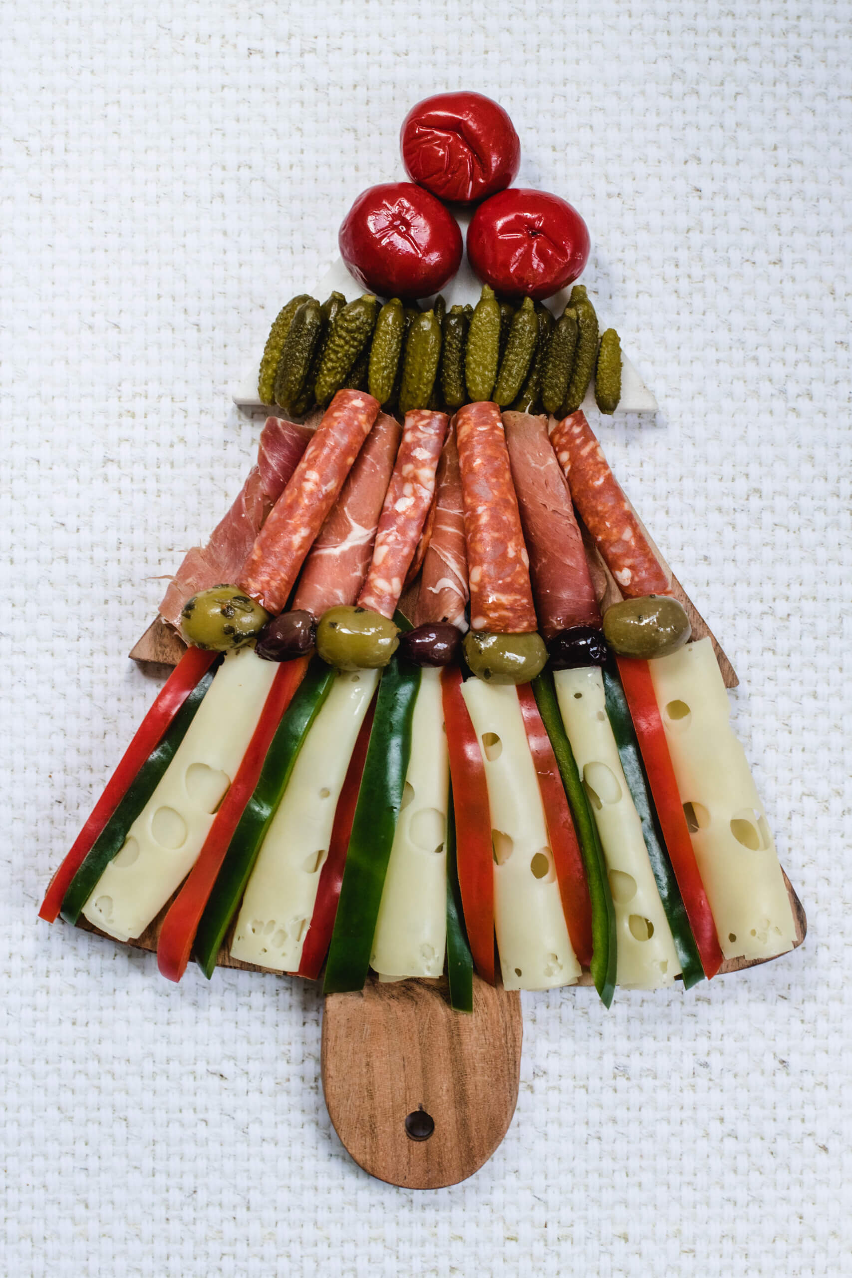 Christmas tree charcuterie board with cheese, capiscum, olives, deli meats, gerkins and stuffed peppers