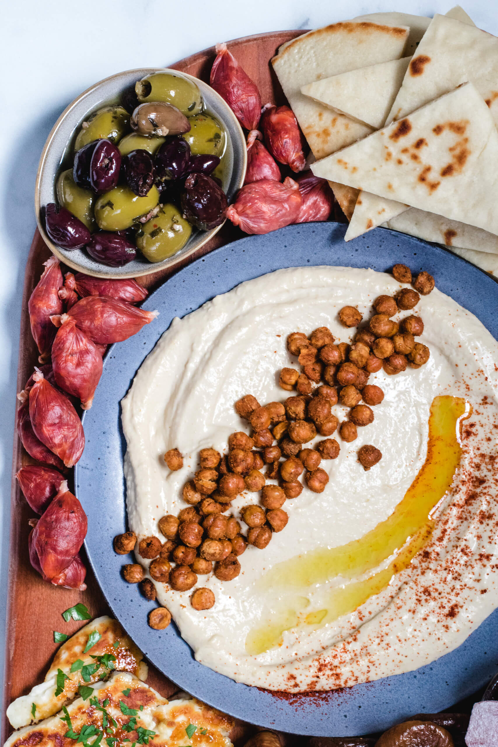 Mediterranean charcuterie board with hummus, olives, chorizo bites and pita bread. 