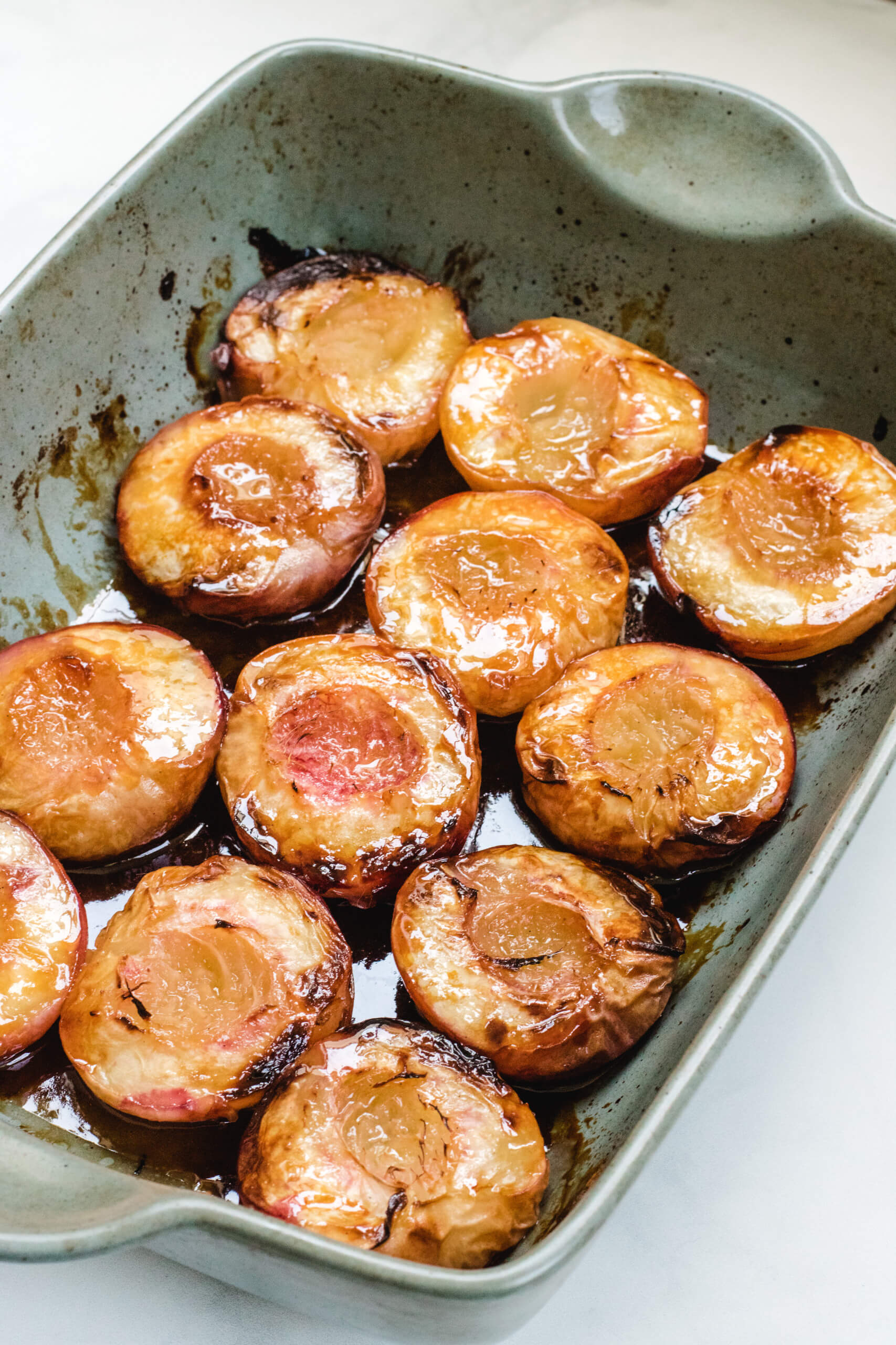 12 halves of peaches roasted in a green baking dish