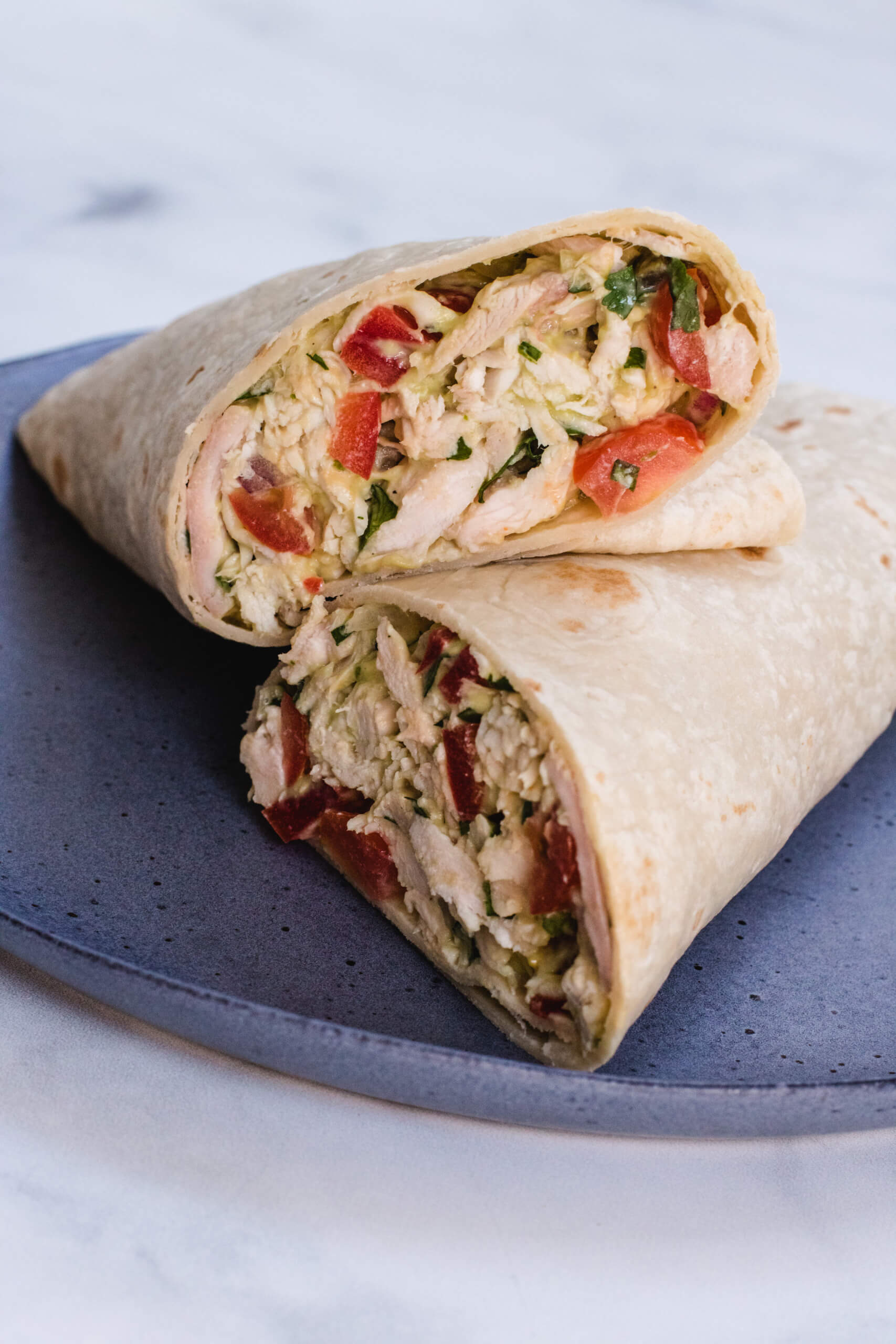 Mexican chicken salad in a wrap on a gray speckled plate. 