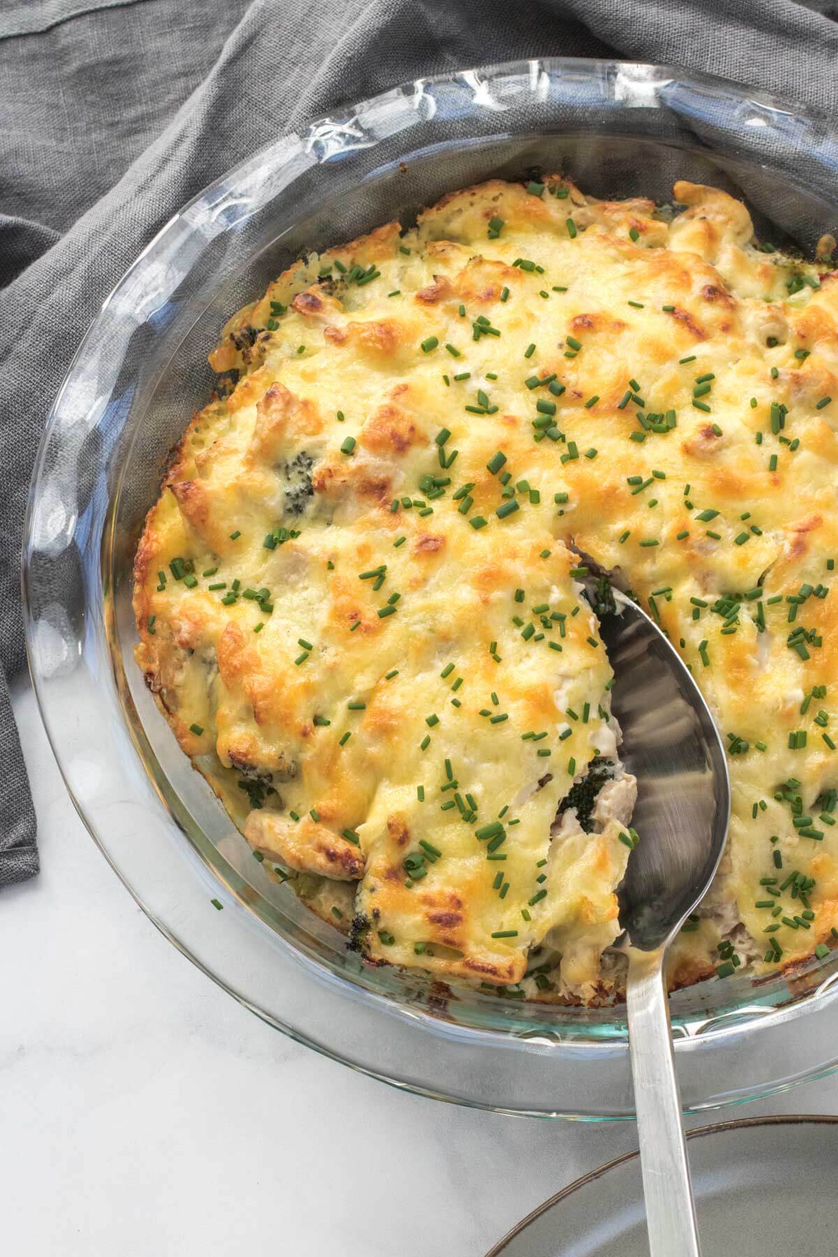 Baking dish with tuna mornay and a serving spoon ready to scoop out a serve.