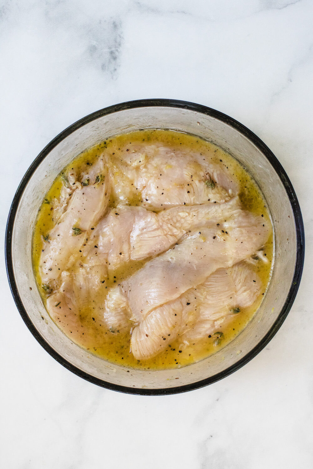 Chicken pieces in the lemon marinade in a bowl.