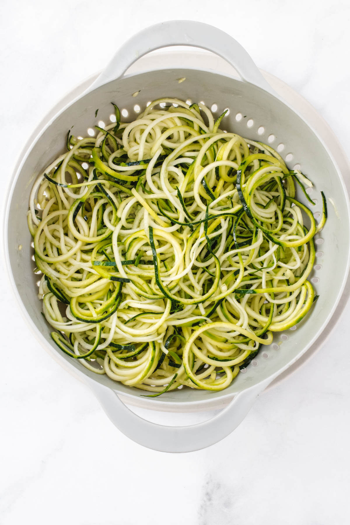 Zucchini noodles in a strainer.