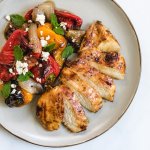 Sliced chicken breast on a plate with roasted pepper salad.